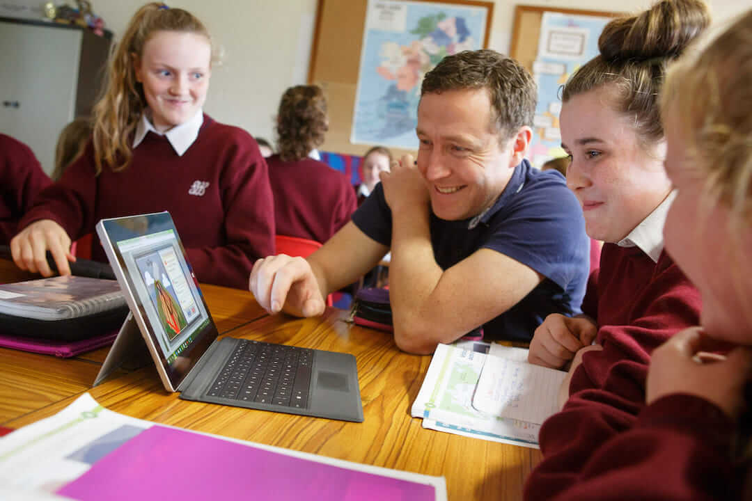 students and their teacher looking at a laptop