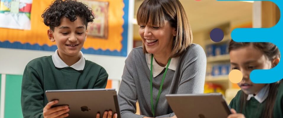 a teacher and students looking at a tablet in the classroom