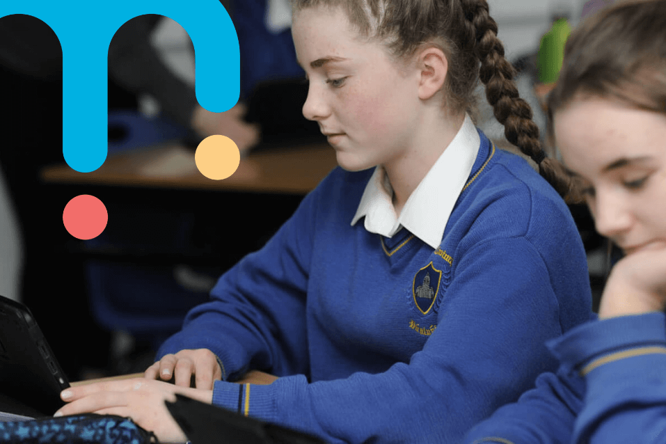 Students in uniform using laptops in class