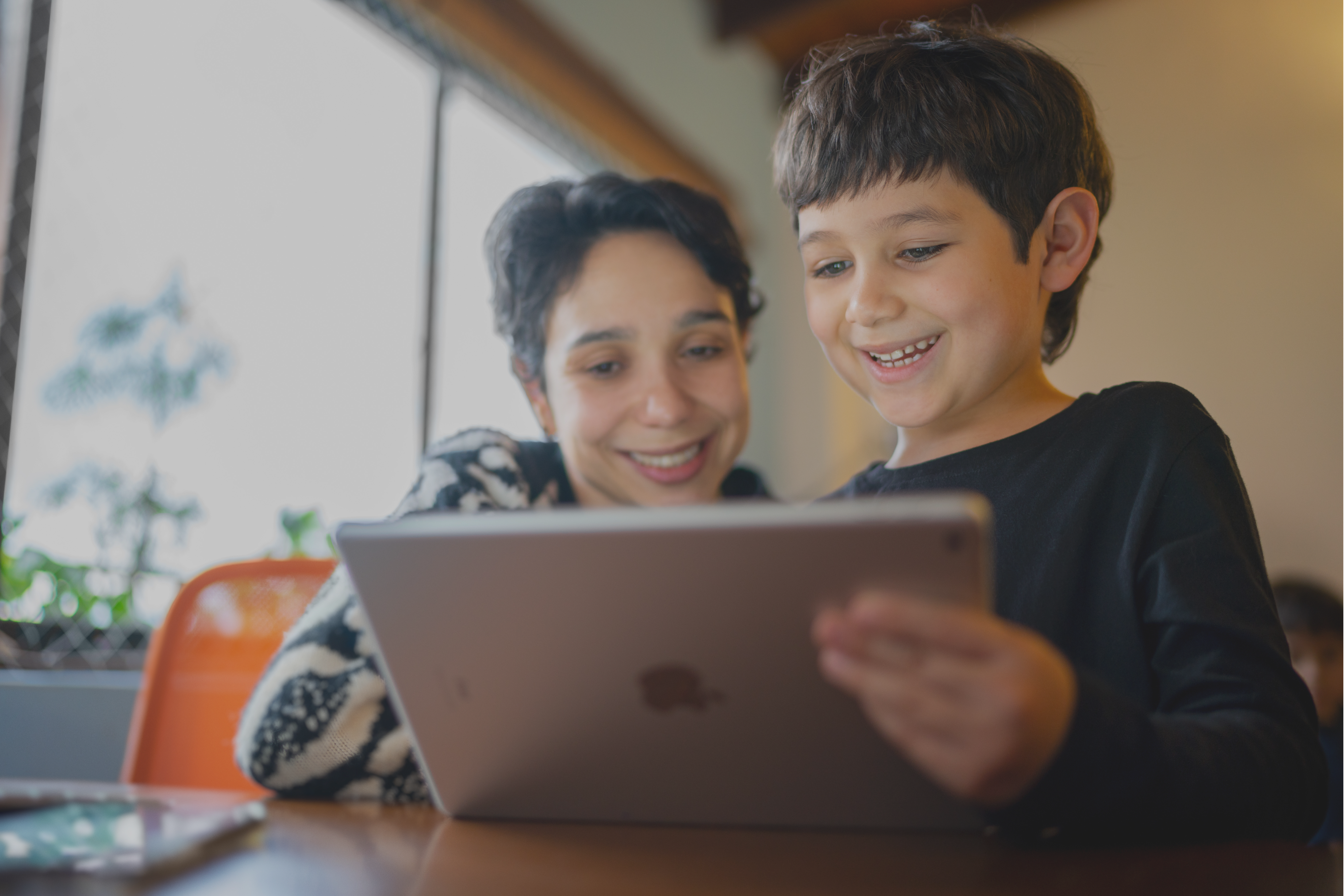 a mother and son looking at an iPad